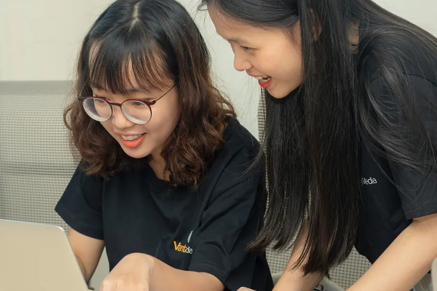 Two college students smiling while they work together on a laptop