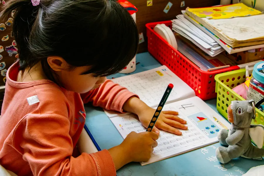 A young girl practicing her handwriting in a workbook